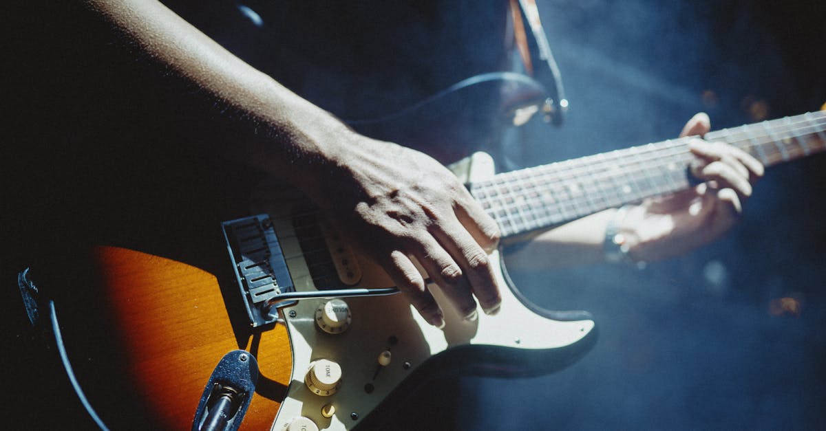 Close-up of a musician playing an electric guitar under stage lights, creating a vibrant atmosphere.