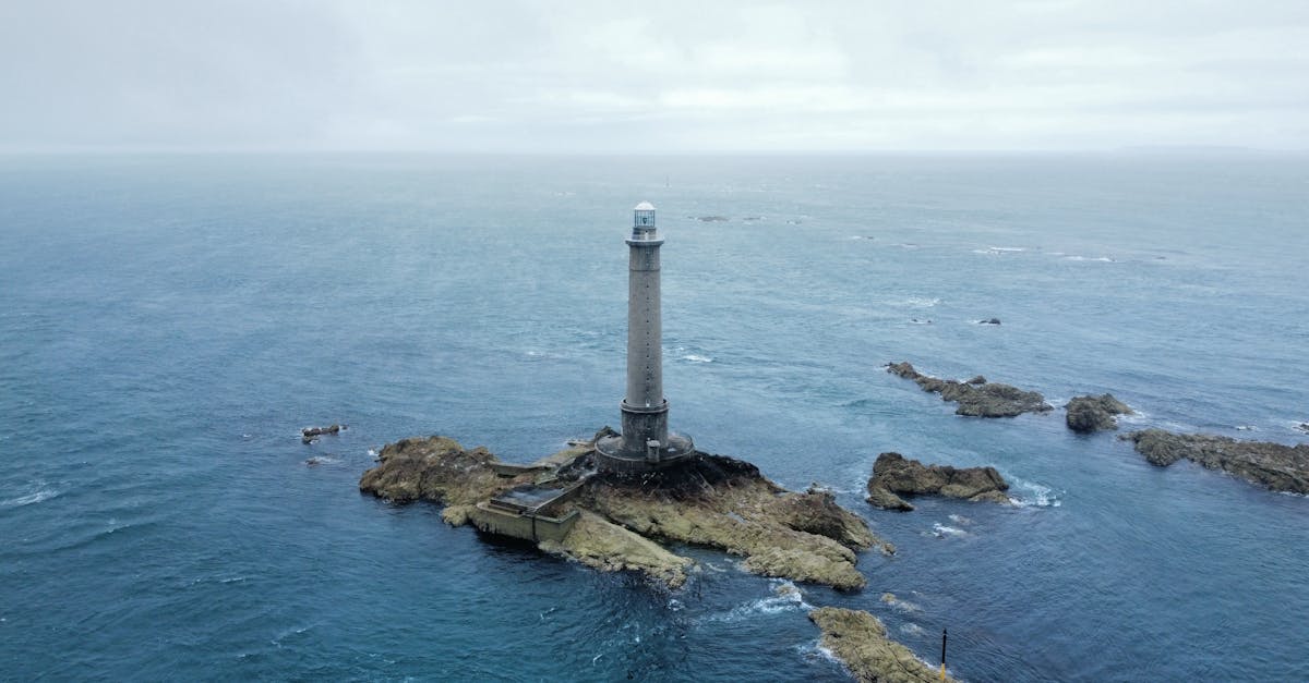 Aerial view of a lone lighthouse on a rocky island surrounded by the ocean.