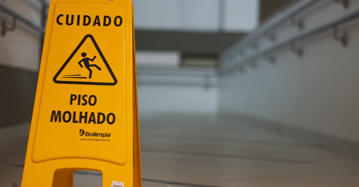 Yellow caution wet floor sign with Portuguese text in an indoor hallway.