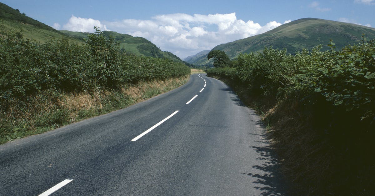 A peaceful country road winding through the scenic Welsh landscape with mountains and hedgerows.