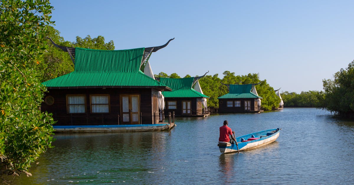 A serene view of floating lodges on the river in The Gambia with a lone boatman.