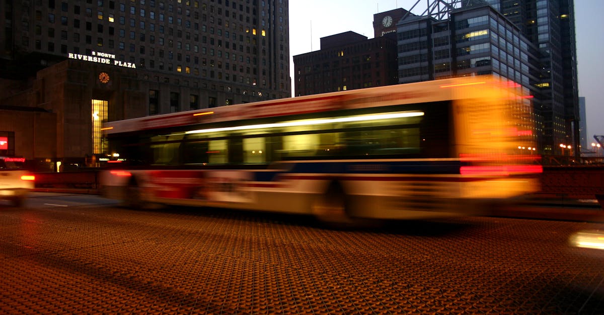 A blurred city bus passes by Riverside Plaza at night, capturing urban movement and architectural backdrop.
