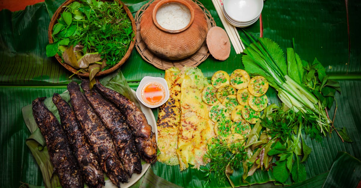Delicious traditional Vietnamese meal featuring grilled fish, rice cakes, and fresh herbs on banana leaves.