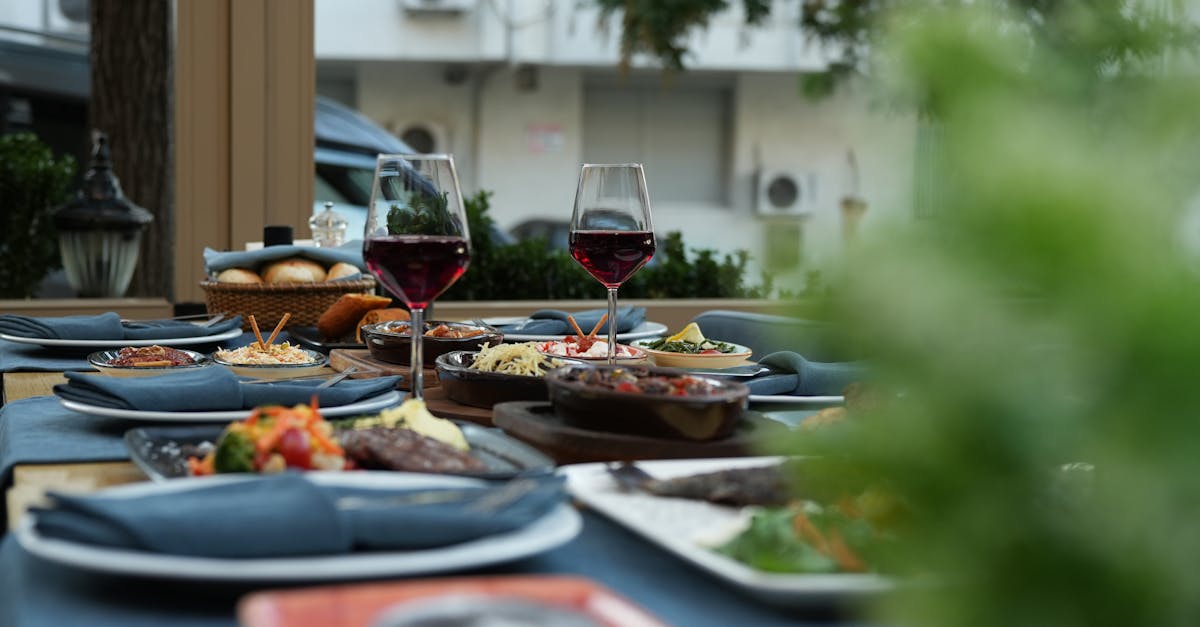 Elegantly set outdoor dining table with wine glasses and assorted dishes, evoking a relaxing dining experience.