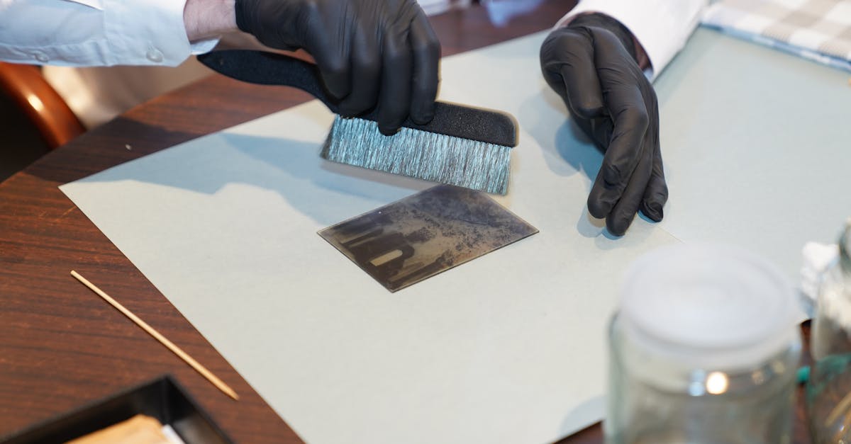 Close-up of photo preservation with a brush on a table, featuring black gloves.