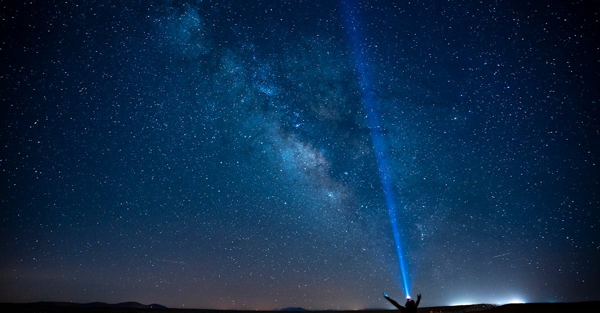 A person stands on a road under the Milky Way, pointing a beam of light into the starry night sky in Karaman, Türkiye.