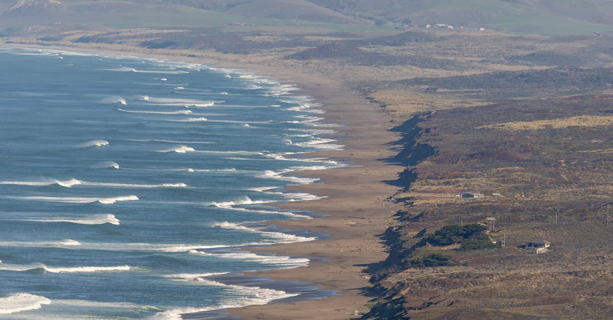 Aerial view of a rugged coastline with waves crashing on a sandy beach.
