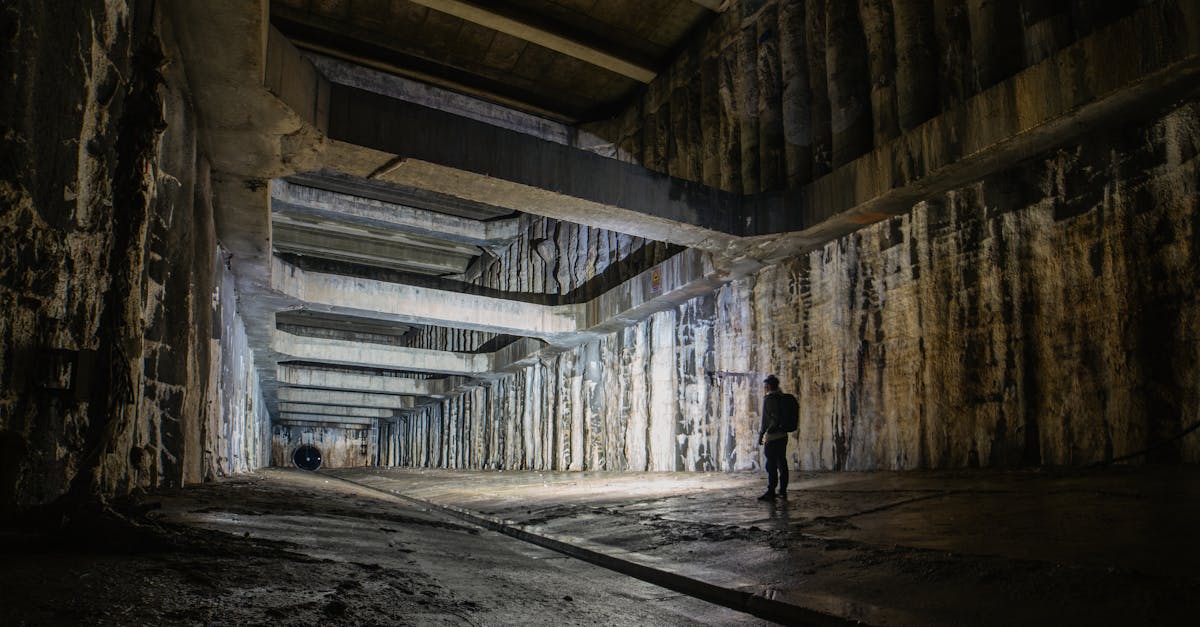 A lone figure explores a vast, cavernous underground space with geometric architecture.
