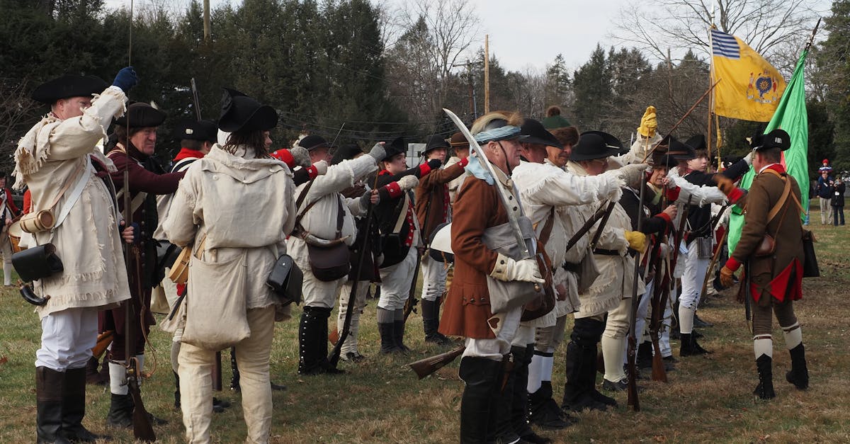 Reenactors in colonial attire perform a Revolutionary War battle re-enactment outdoors.