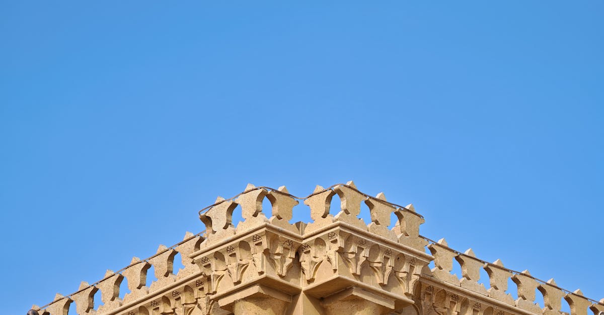 A detailed view of intricate architectural designs on a building set against a clear blue sky.