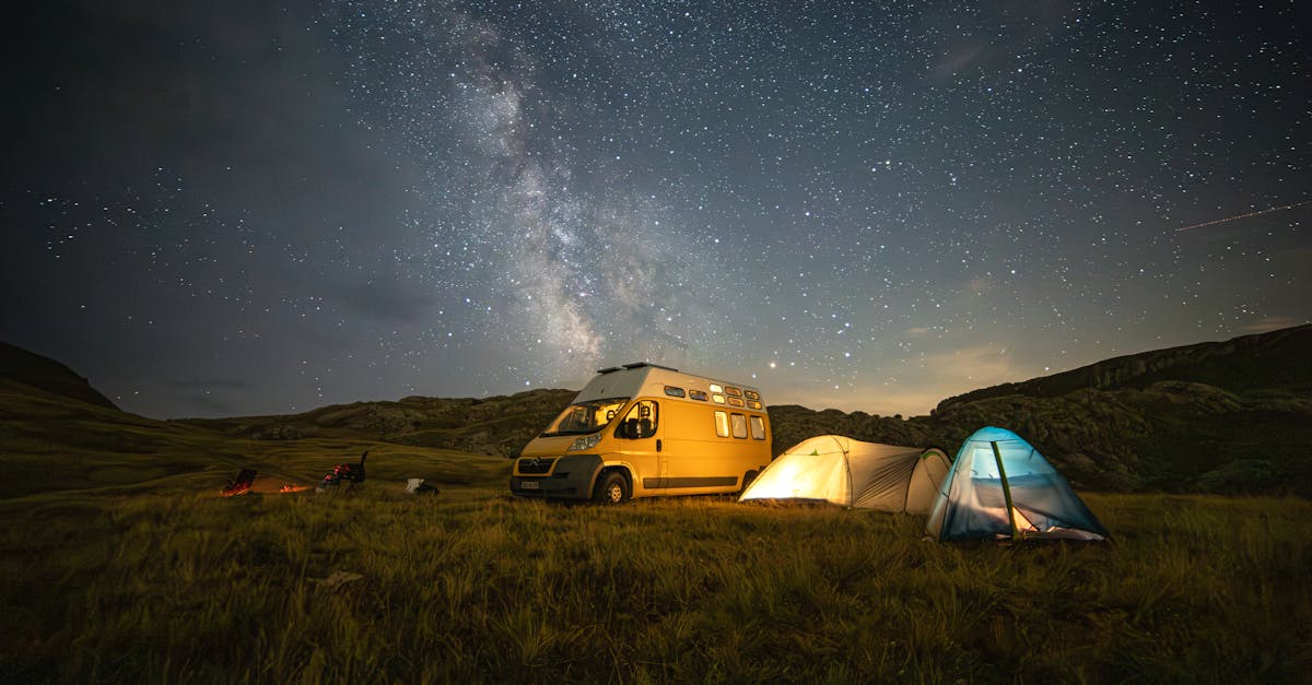 Experience the serenity of a starlit night camping in nature with a van and glowing tents.