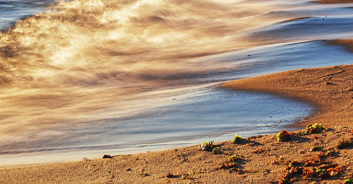 A serene beach scene capturing golden waves under the setting sun, creating a peaceful coastal atmosphere.