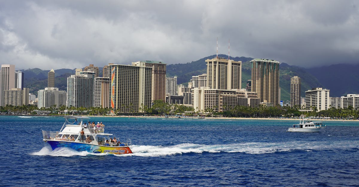 A vibrant tour boat cruises in front of Honolulu's iconic skyline on a sunny day.