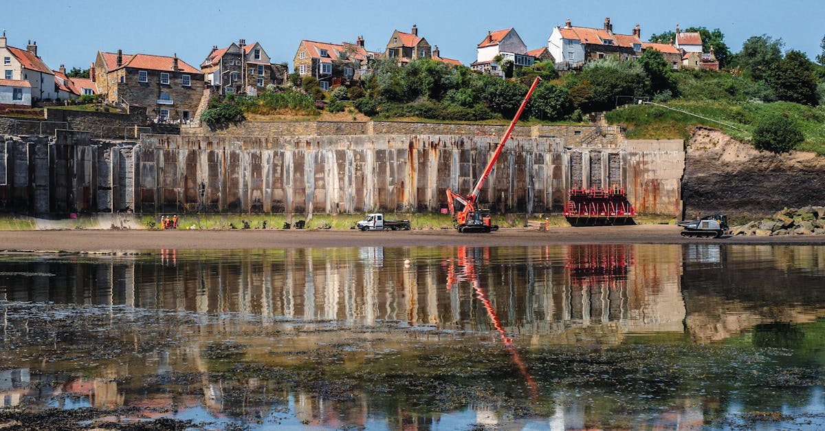 Construction site at Robin Hood's Bay with a sea wall and reflections in the water.