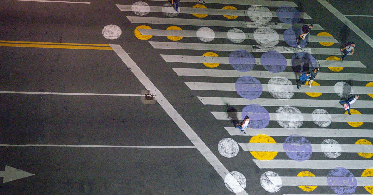 Overhead view of a colorful crosswalk with people walking at night in a city.