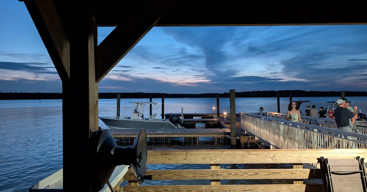 A serene evening view of the waterfront deck in Mount Pleasant, featuring people and boats under a twilight sky.