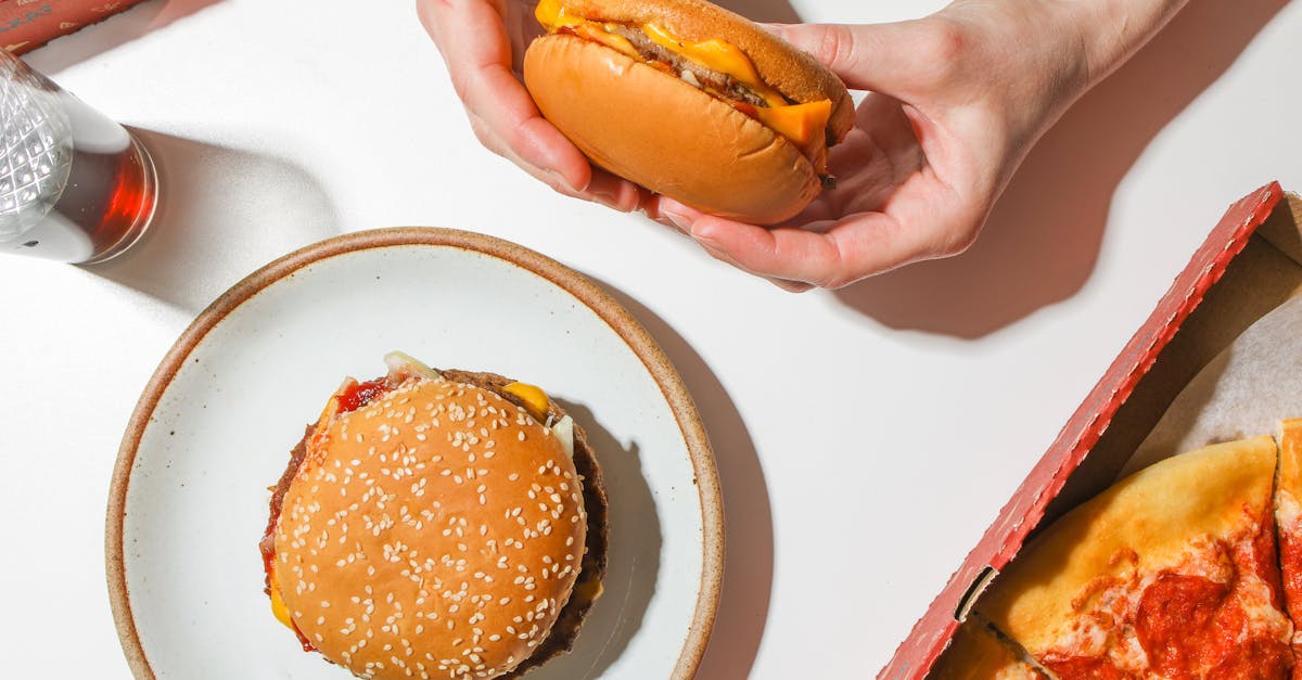 Cheeseburger with sesame seed bun and pepperoni pizza on a table, perfect for a tasty meal.
