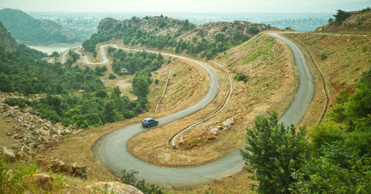 Winding mountain road in Indian countryside surrounded by lush greenery and hills.