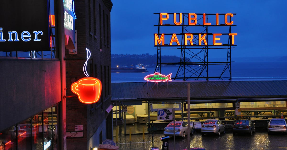 Vibrant nighttime view of Seattle's Public Market with neon coffee and market signs illuminated.