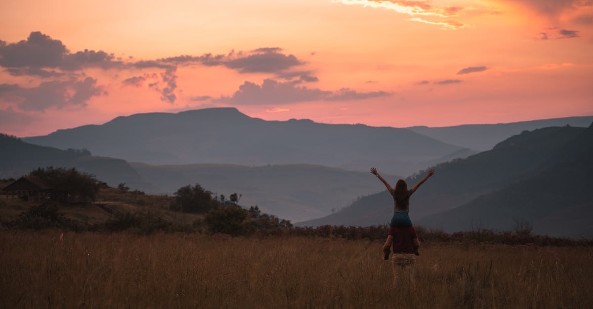 A couple embraces the vibrant sunset over South African mountain scenery.