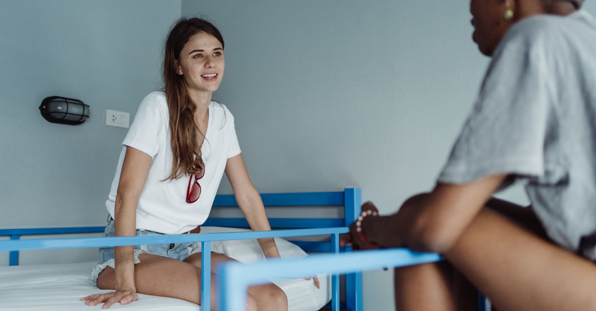 Two women engaged in a friendly conversation in a hostel room with bunk beds.