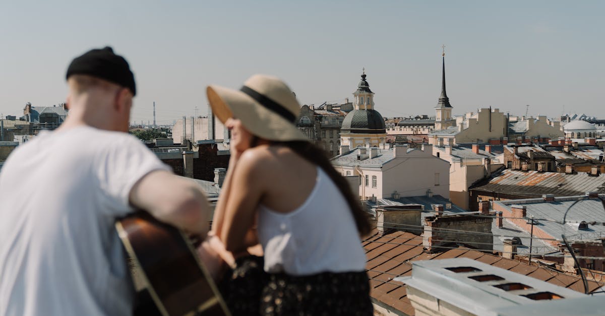A couple enjoys music on a rooftop with a city view, sharing a romantic and relaxing summer moment.
