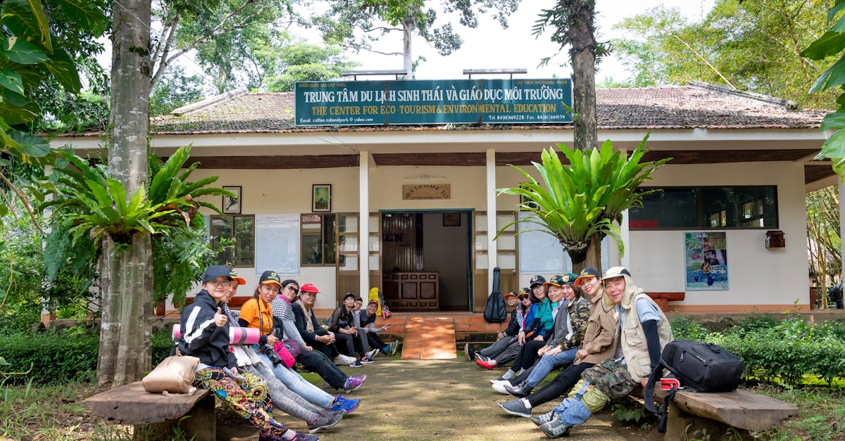 Team of travelers with backpacks waiting for start of trekking excursion while sitting near entrance of tourist agency