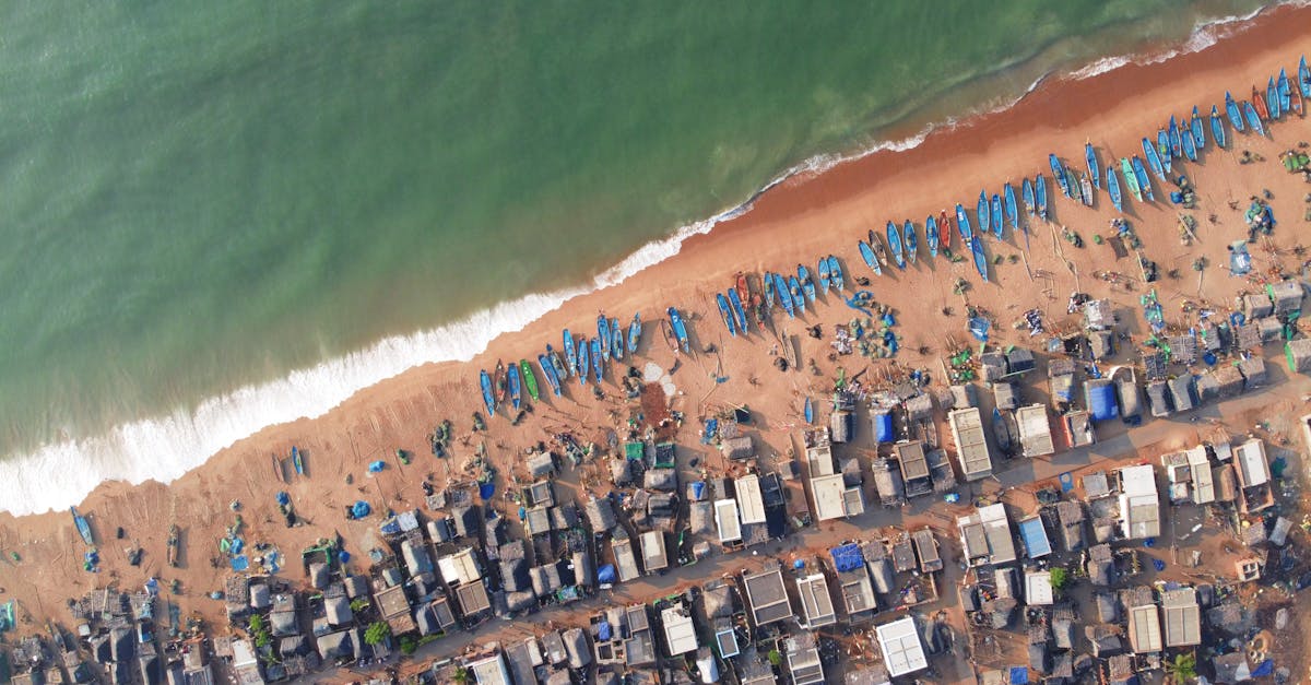 A stunning aerial image capturing the vibrant fishing village along the Odisha coastline, lined with colorful boats and coastal homes.