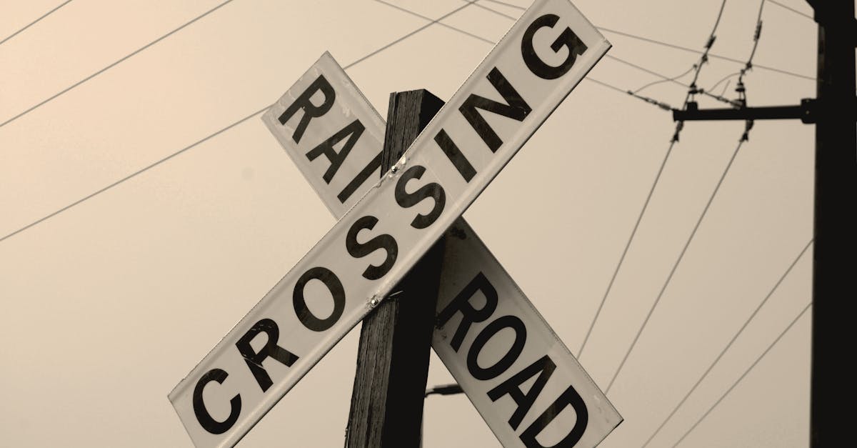 Low angle shot of a railroad crossing sign with electric wires in the evening sky.