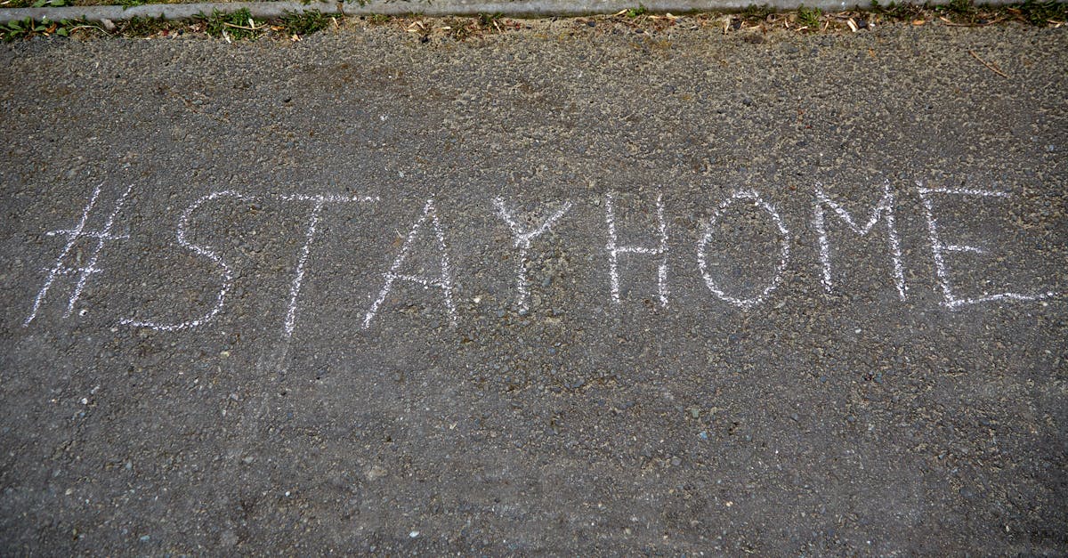 Chalk-written #StayHome message on asphalt during daylight, emphasizing safety and health.