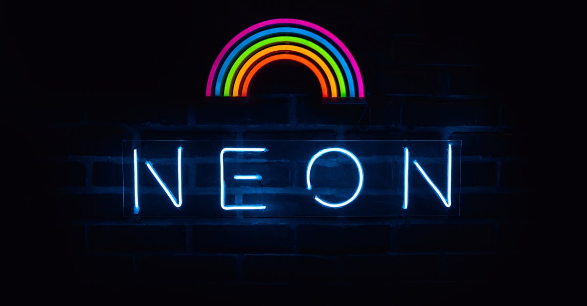 Colorful neon rainbow and text sign against a dark backdrop.