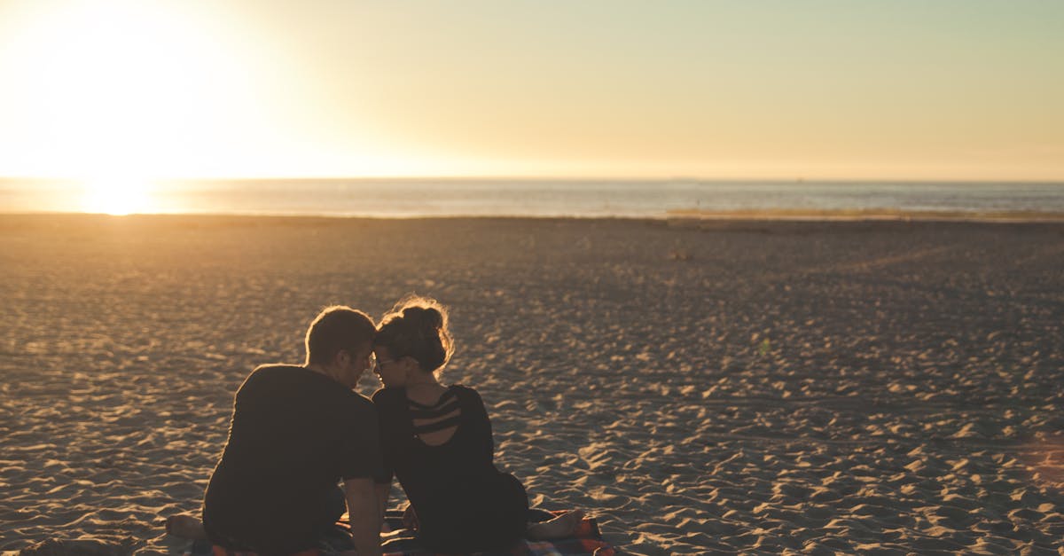 A couple enjoys sunset together on a sandy beach, capturing a moment of love and togetherness.