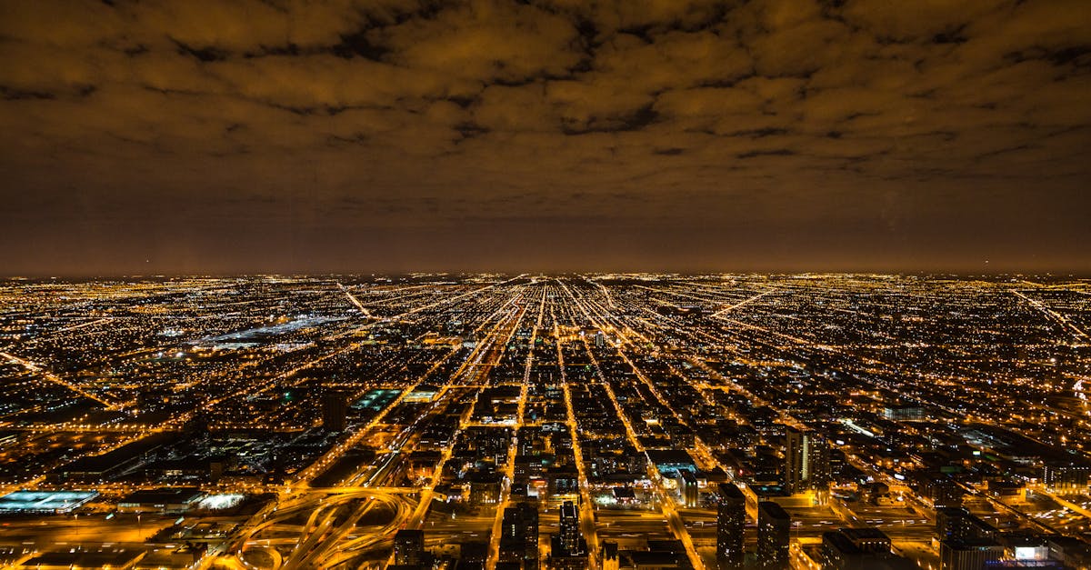 A breathtaking aerial view of Chicago at night, showcasing vivid city lights and a dramatic sky.