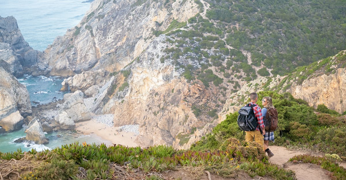 Two hikers explore the scenic cliffs of Portugal surrounded by ocean views and rugged terrain.