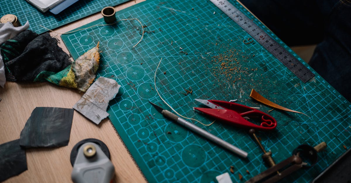 A cluttered craft workspace with various DIY tools and materials on a cutting mat.
