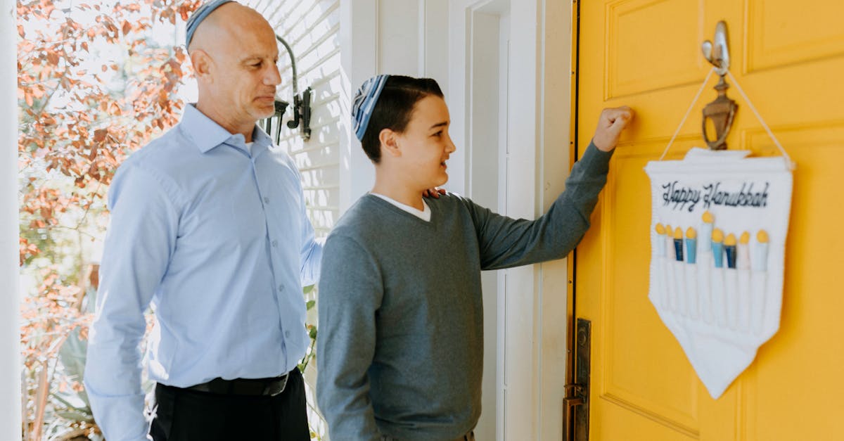 A father and son knocking on a yellow door with a Happy Hanukkah sign, celebrating the Jewish holiday.