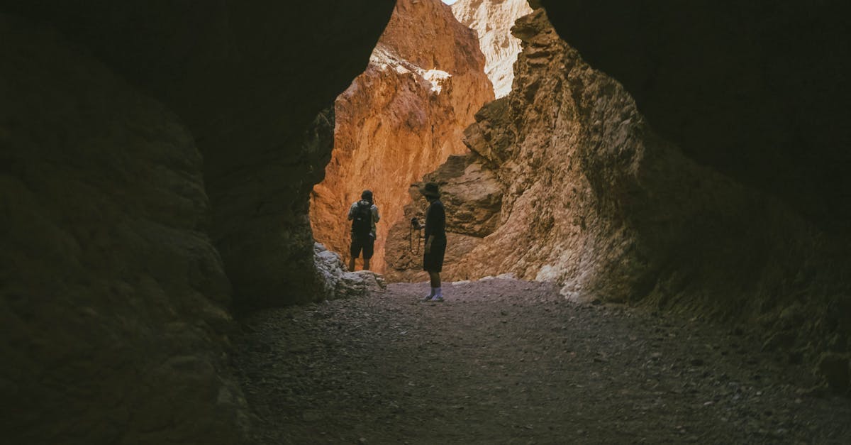 Two hikers venture through a rocky canyon illuminated by natural light, capturing the essence of exploration.