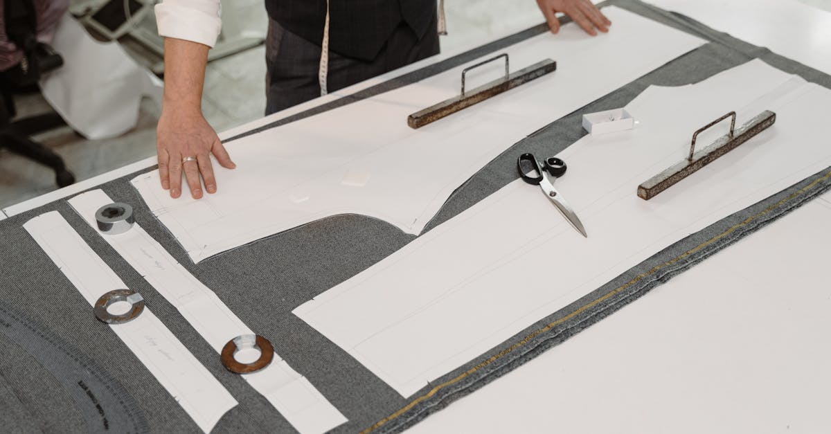 Hands of a tailor working with fabric and patterns in a workshop, showcasing traditional craftsmanship.