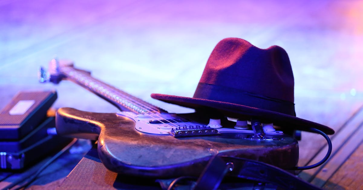 Close-up of an electric guitar and hat on stage under vibrant lights.