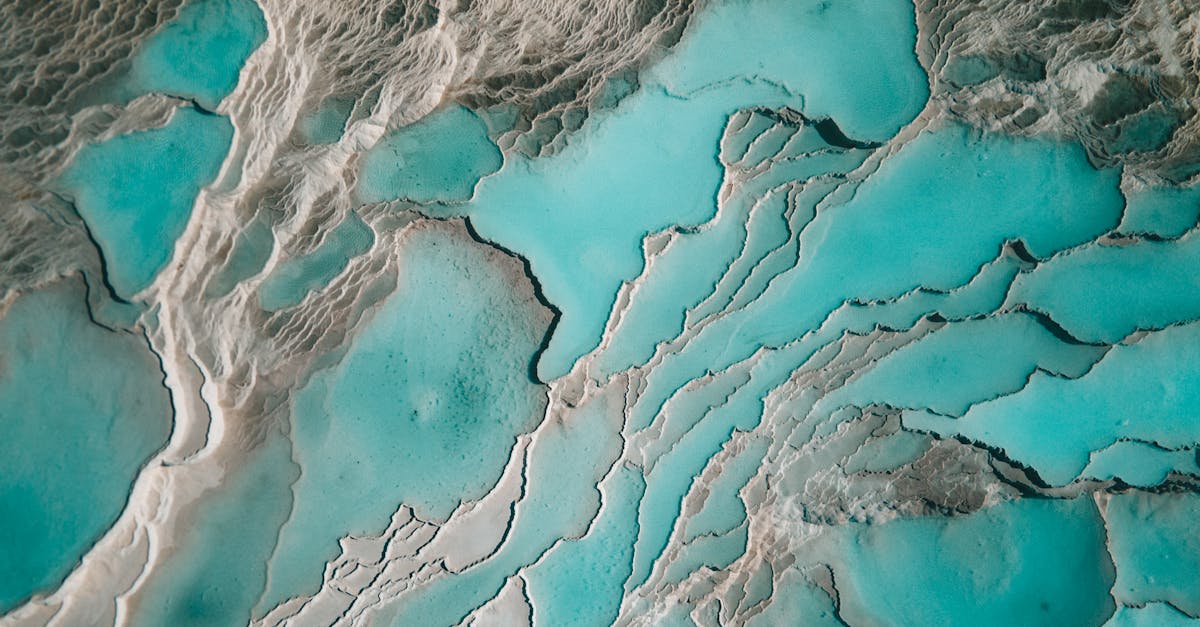 Beautiful aerial view of turquoise thermal pools and white mineral formations, resembling natural abstract art.