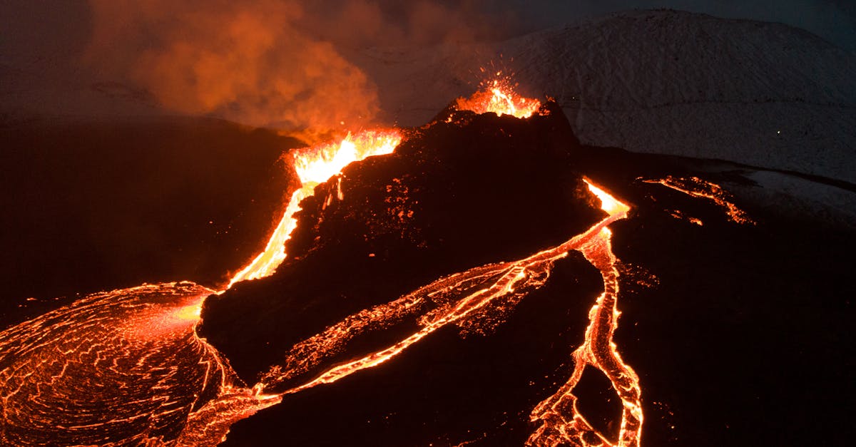 Captivating aerial view of a volcano eruption with flowing lava under the night sky.
