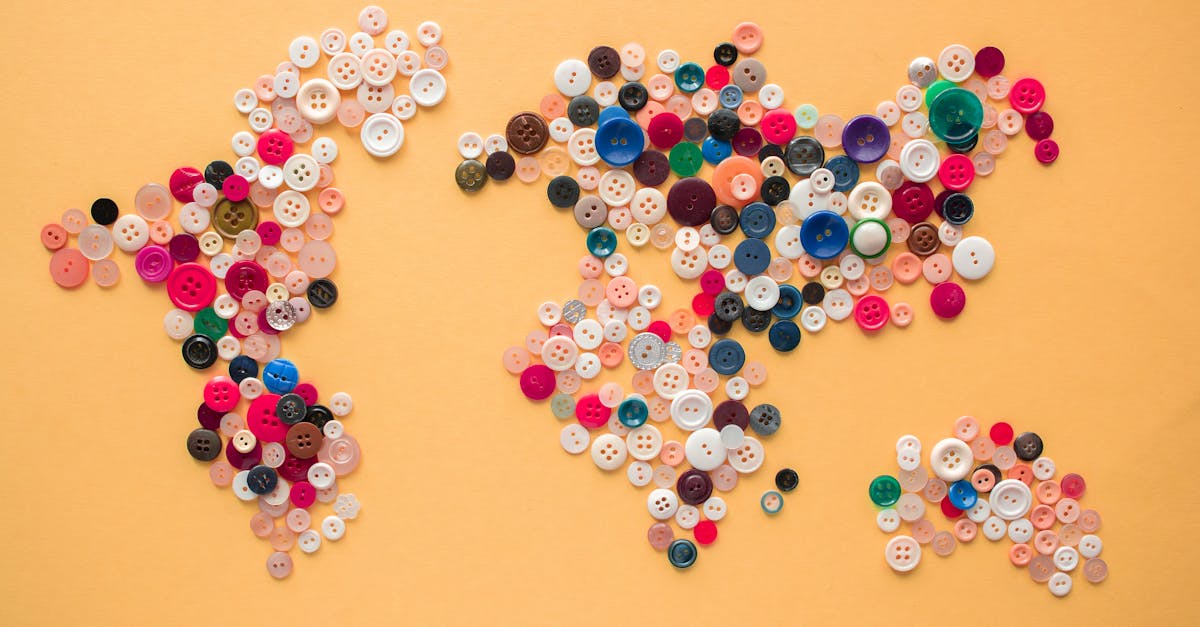 Top view of multicolored buttons of various size arranged on yellow background making world map