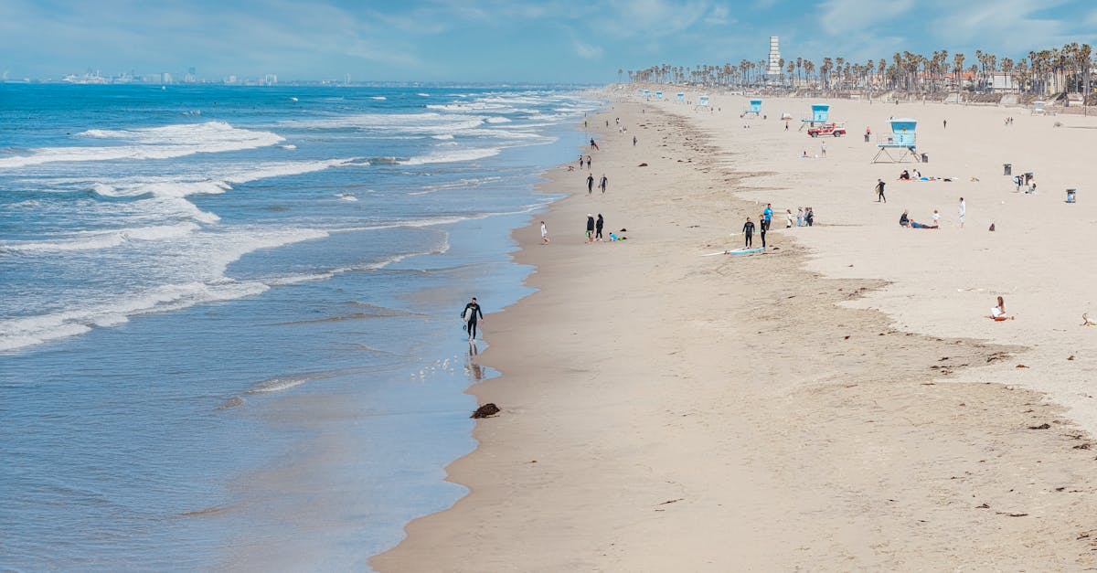 A vibrant beach scene in California featuring waves, beachgoers, and lifeguard towers on a sunny day.