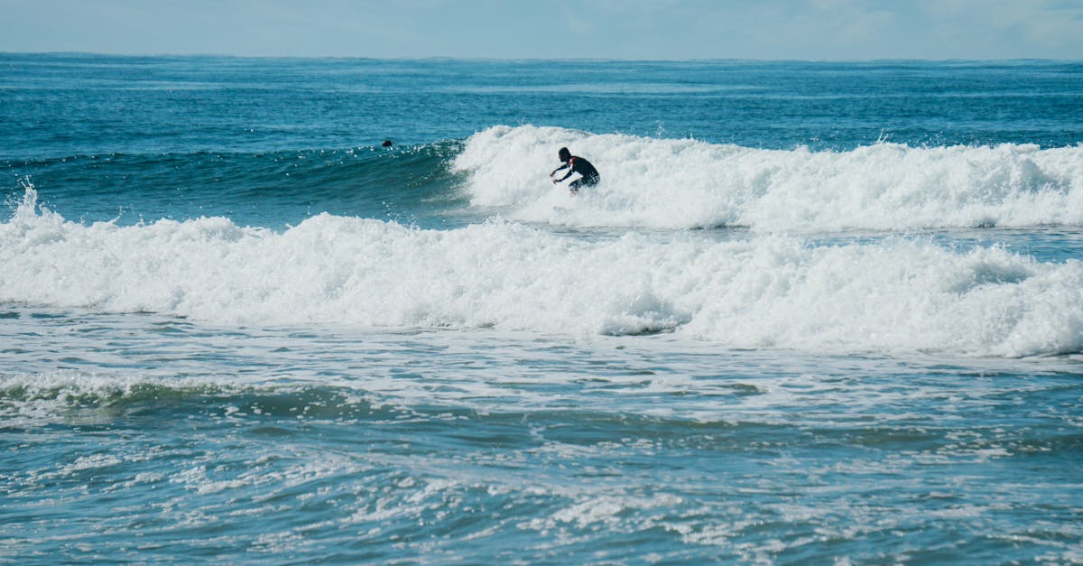 A surfer skillfully rides a wave in a sunny ocean view, epitomizing the thrill of water sports.