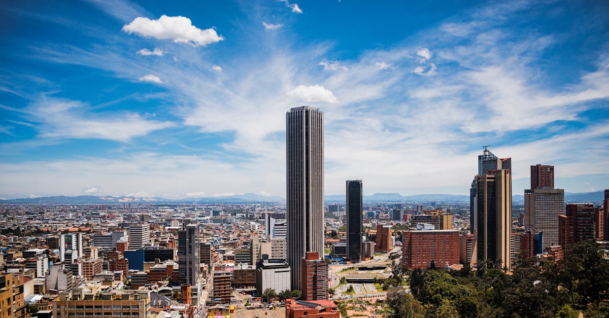 A breathtaking cityscape of Bogotá with the iconic Colpatria Tower under a vibrant blue sky.