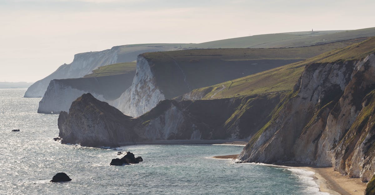 Stunning coastal landscape featuring rugged cliffs and serene sea under bright daylight.