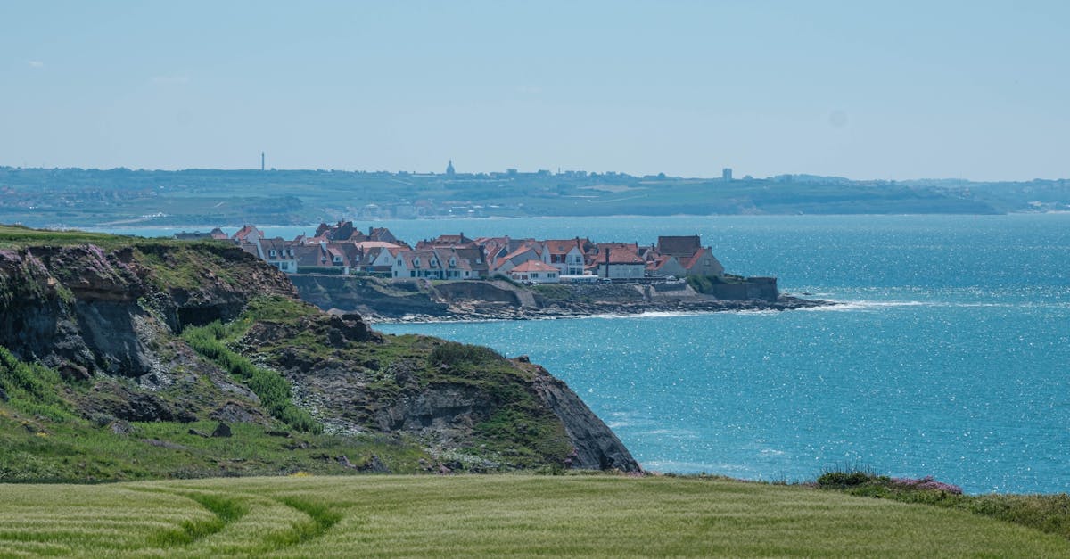 Scenic coastal town atop cliffs with clear skies and blue sea on a summer day.