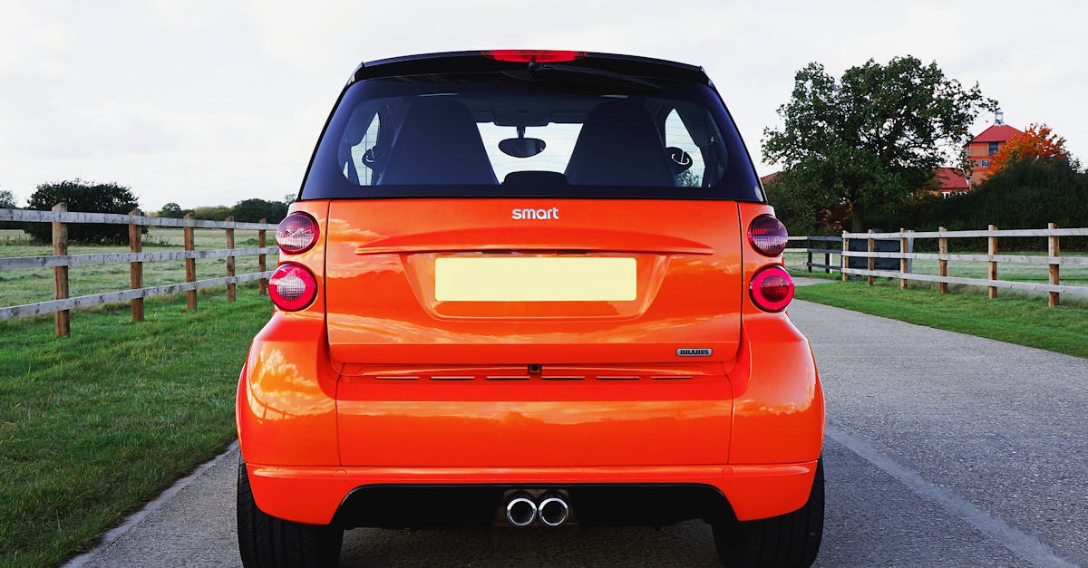 A vibrant orange Smart car parked on a rural road in Knebworth, England.