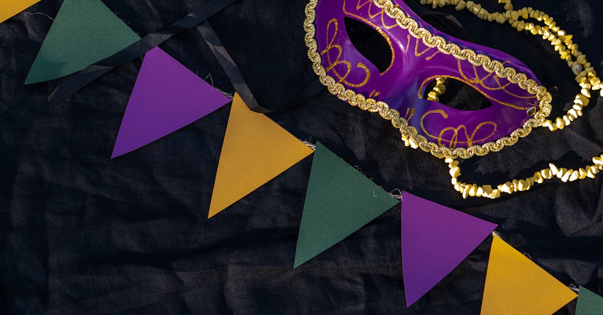 Colorful Mardi Gras mask and pennants on black fabric capturing festive spirit.