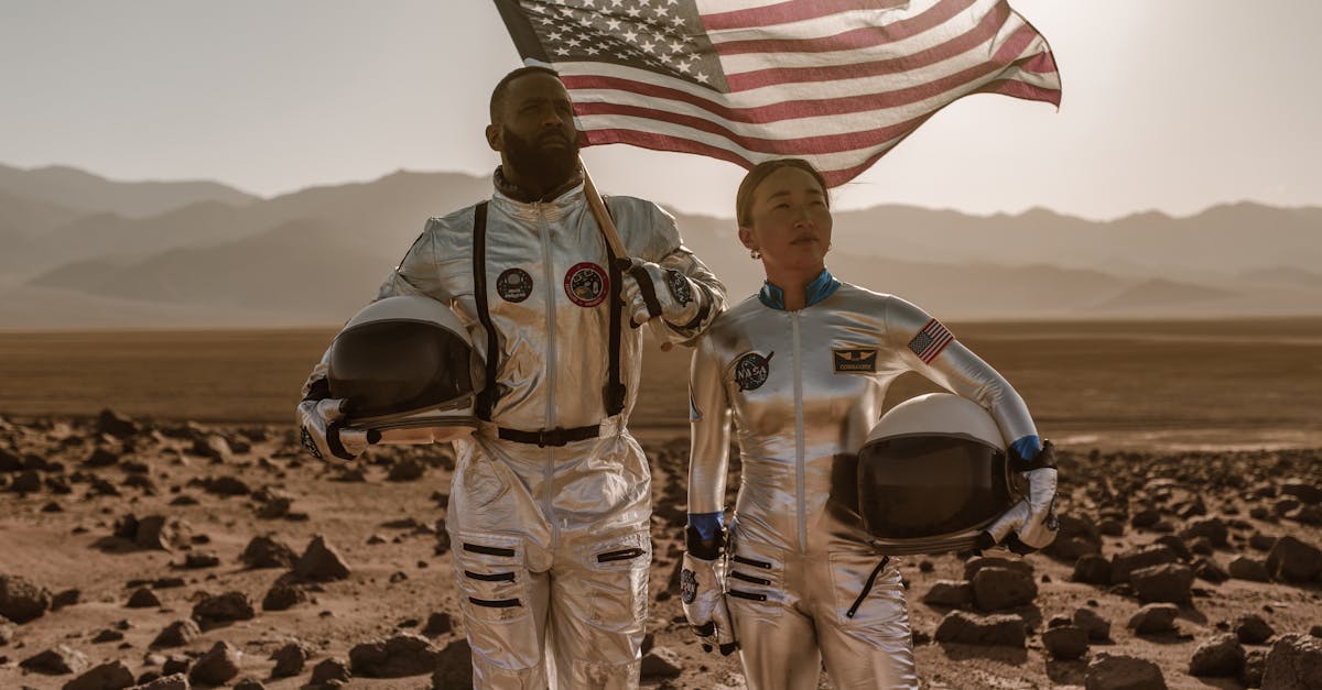 Two astronauts in space suits with an American flag in a desert environment resembling Mars.